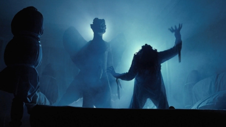 A contorted Regan (Linda Blair) reaches up with the statue of Pazuzu over her in The Exorcist