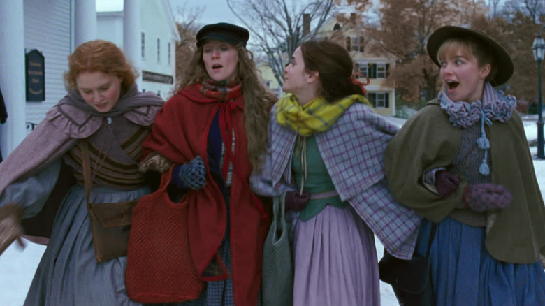 Eliza Scanlen, Saoirse Ronan, Emma Watson, and Florence Pugh as Beth, Jo, Meg, and Amy walking arm in arm in the snow in Little Women