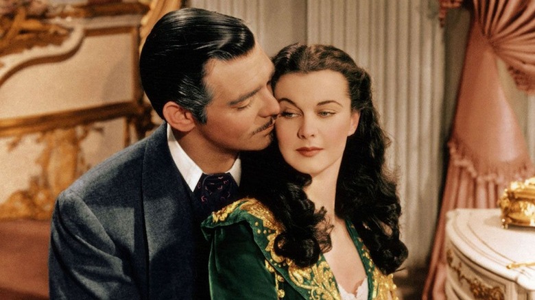 Clark Gable as Rhett Butler and Vivien Leigh as Scarlett O'Hara in Gone With The Wind, with Rhett embracing Scarlett from behind and she turns slightly towards his face.