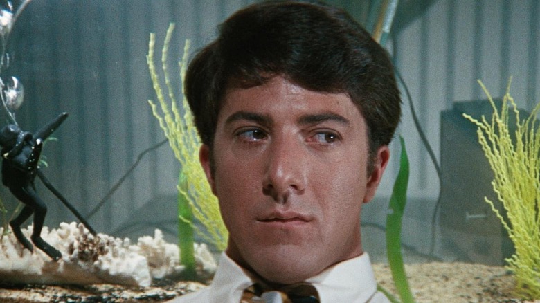 Dustin Hoffman as Benjamin Braddock in The Graduate, seen in a medium shot backgrounded by an aquairum.