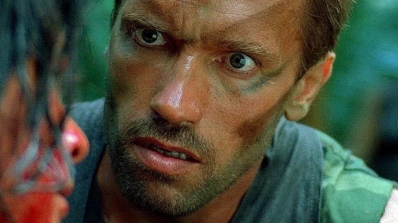 A close-up of Arnold Schwarzenegger as Alan "Dutch" Schaefer in Predator, with a little bit of war paint on and looking manic.