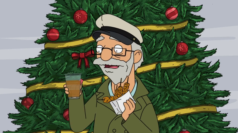 An old man in a captain's hat holds a drink and a bag of fried food