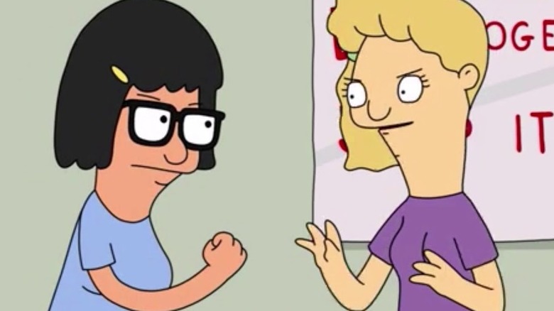 Tina brandishes her fist at a blonde girl