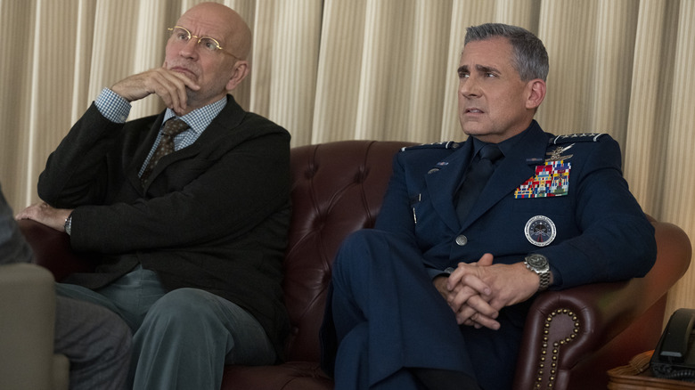 Dr. Adrian Mallory (John Malkovich) and Mark R. Naird (Steve Carell) sitting on a couch on Space Force