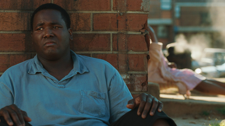 Michael Oher (Quinton Aaron) leaning against brick wall in The Blind Side