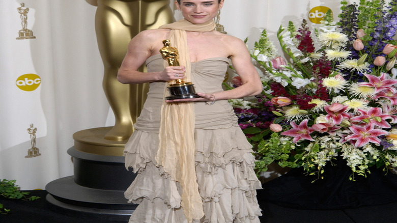 Jennifer Connelly in beige dress holding Oscar in front of flowers and large Oscar statue in 2002