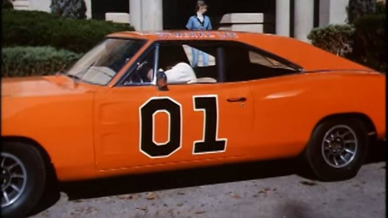 Bo (Luke Schneider) and Luke Duke (Tom Wopat) inside the General Lee on The Dukes of Hazzard