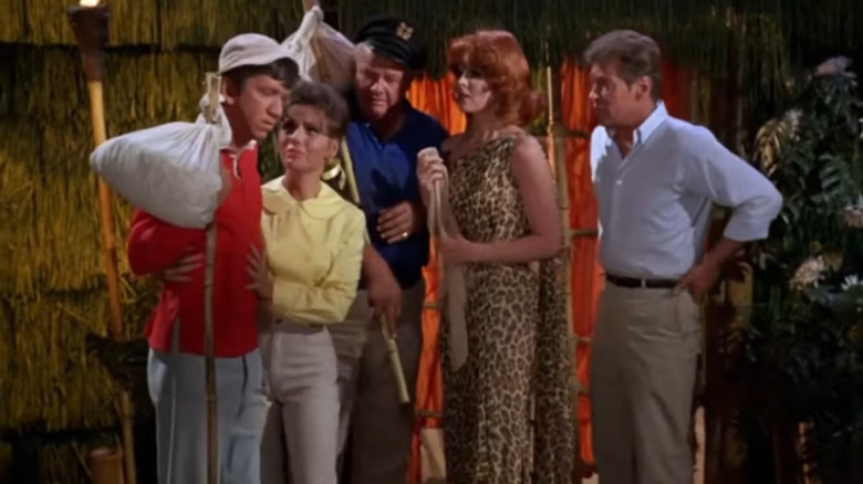 The castaways talking to Gilligan (Bob Denver) holding a bindle on Gilligan's Island