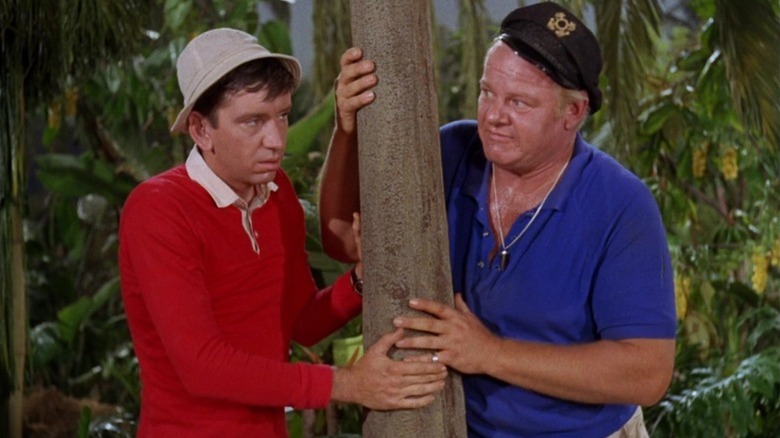 Gilligan (Bob Denver) and the Skipper (Alan Hale Jr.) holding a tree on Gilligan's Island