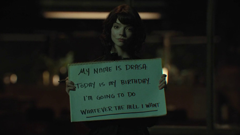 Anya Taylor-Joy as Drasa holding a sign that says "My name is Drasa. Today is my birthday. I'm going to do whatever the hell I want" in The Gorge