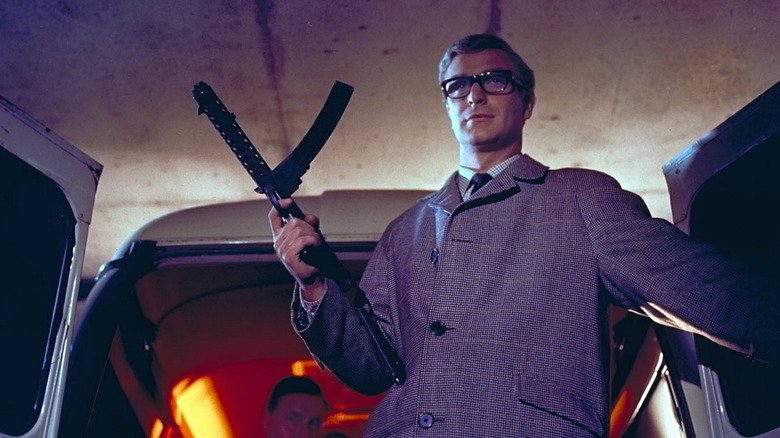Michael Caine standing tall with machine gun