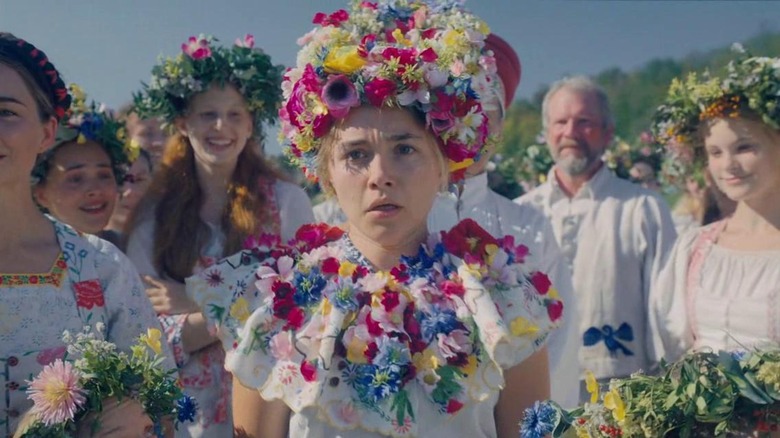 Dani (Florence Pugh) in her May Queen flower hat and necklace, surrounded by cultists, in Midsommar