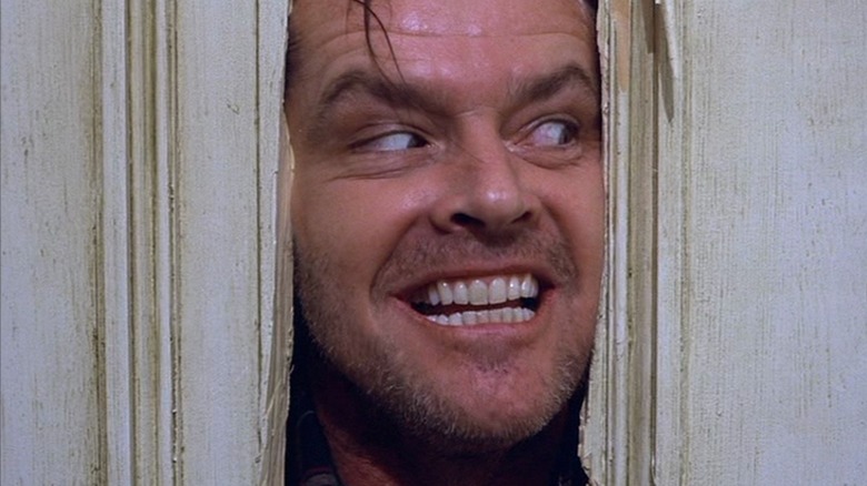 Jack (Jack Nicholson) sticks his face through the splintered closet door in The Shining