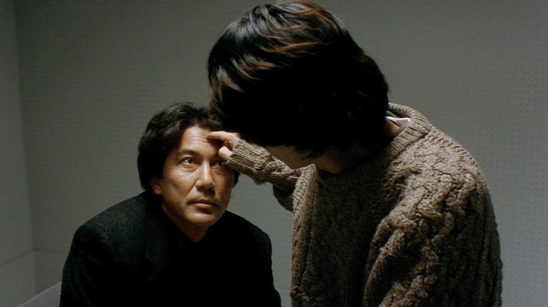 Kōji Yakusho as Kenichi Takabe having his head touched in a doctor's office in Cure