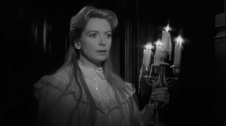 Deborah Kerr as Miss Giddens in nightgown holding candle in doorway in The Innocents