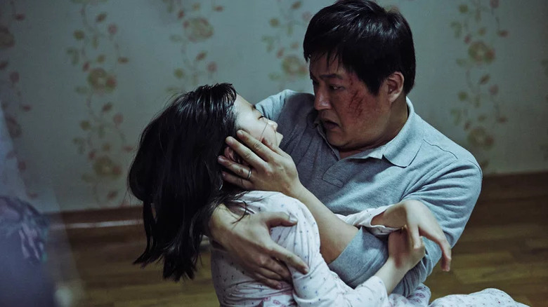 Kwak Do-won as Jong-goo with scratches on his face holding young girl Kim Hwan-hee as Hyo-jin in The Wailing