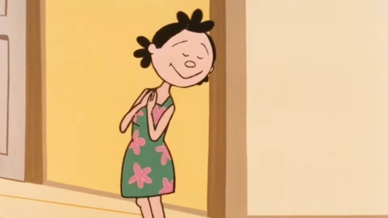 Sazae Fuguta wearing a green dress with pink florals, cupping her hands together and smiling with her eyes closed on Sazae-san
