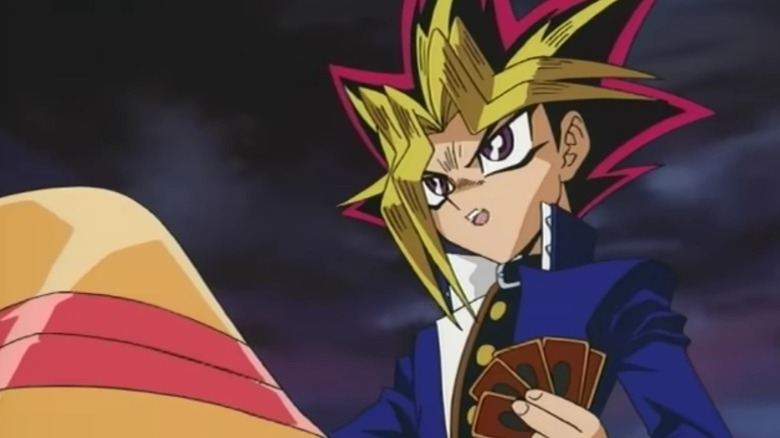 Yugi Muto holding a card during a duel on Yu-Gi-Oh! Duel Monsters