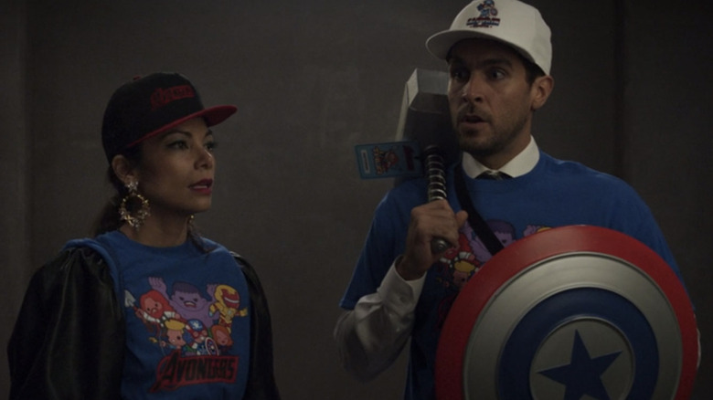 Ginger Gonzaga as Nikki Ramos and Josh Segarra as Pug wearing knockoff Avengers merch in She-Hulk