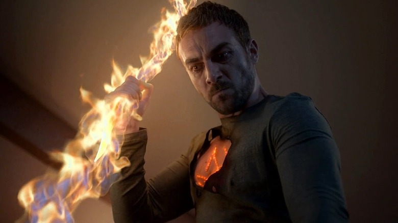 Tom Austen as Daimon Helstrom weilding a flaming weapon in Helstrom