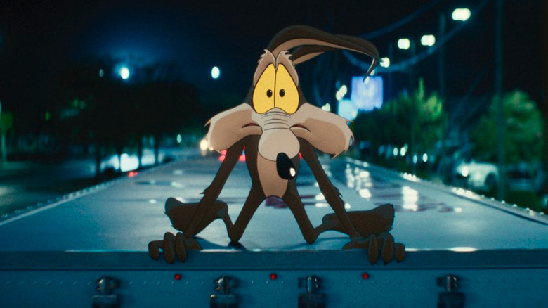 Wile E. Coyote looks worried on top of a box truck driving down a road at night in Coyote vs ACME