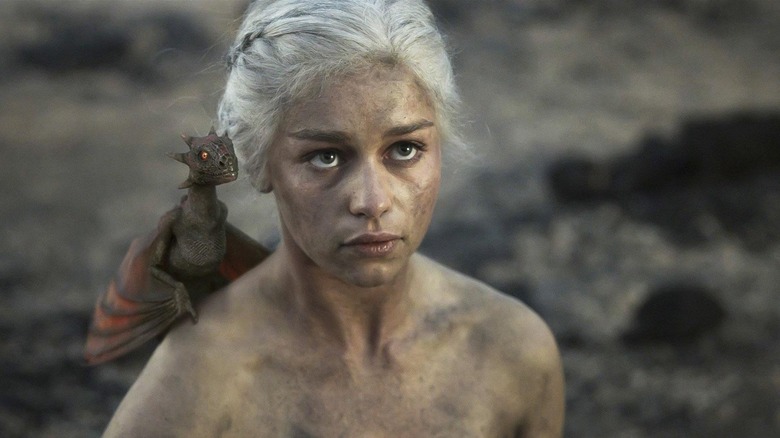Emilia Clarke as Daenerys naked and covered in ash with baby Drogon on her shoulder in Game of Thrones