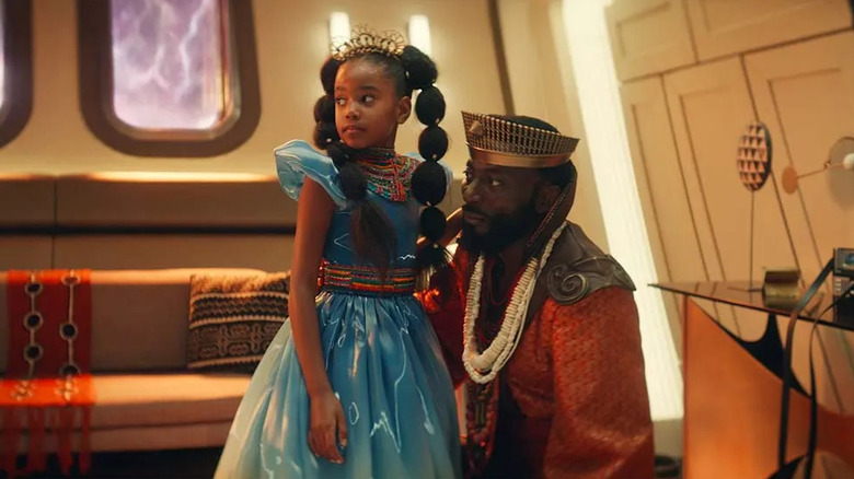 Rukiya (Sage Arrindell) in a princess outfit stands next to a kneeling Joseph M'Benga (Babs Olusanmokun) in a fantasy outfit in Star Trek: Strange New Worlds