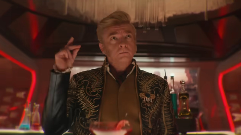 Trelane (Rhys Darby) snaps his fingers behind a bar in Star Trek: Strange New Worlds