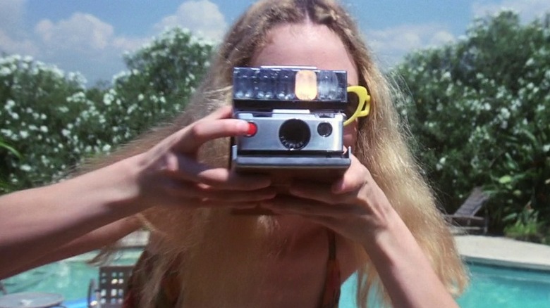 Heather Graham as Brandy / Rollergirl in Boogie Nights, pointing her polaroid camera directly at the camera.