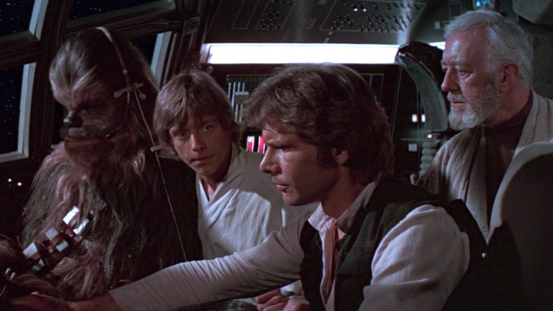 Mark Hamill as Luke Skywalker, Harrison Ford as Han Solo, Alec Guinness as Obi-Wan Kenobi, and Peter Mayhew as Chewbacca, all sitting around the cockpit of the Millennium Falcon.