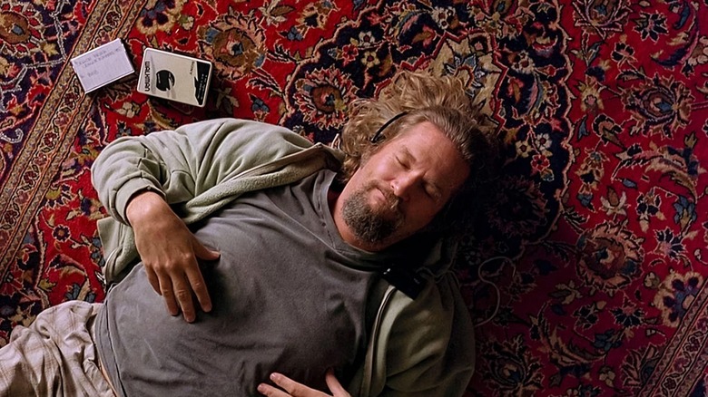 Jeff Bridges as The Dude in The Big Lebowski, laying on his rug with headphones on and eyes closed.