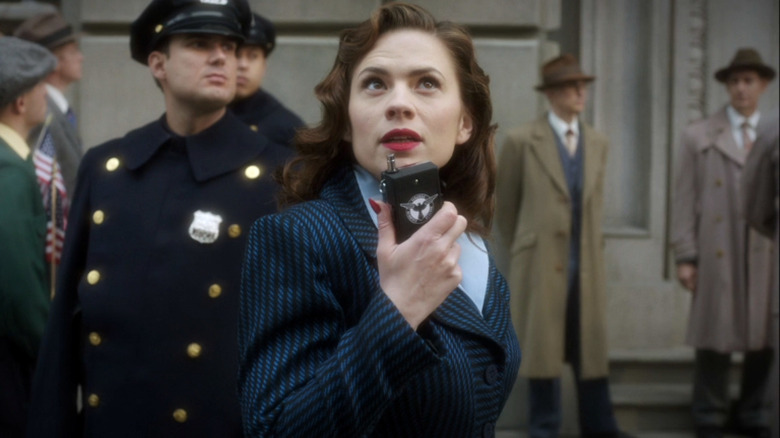 Haley Atwell as Peggy Carter holds a radio and looks up on Agent Carter