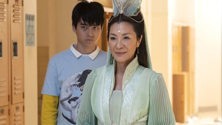 Jimmy Liu as Wei-Chen stands behind Michelle Yeoh as Guanyin Pusa while in a school on American Born Chinese