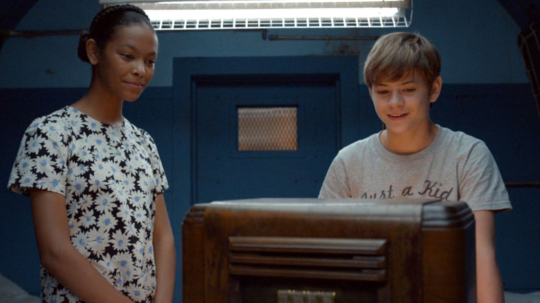 Kyliegh Curran as Harper Dunn stands next to Preston Oliver as Griffin Campbell while they look at an object on The Secrets of Sulphur Springs