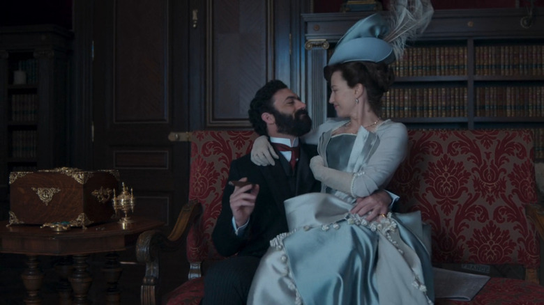 Bertha Russell (Carrie Coon) sitting on husband George's lap (Morgan Spector) in The Gilded Age