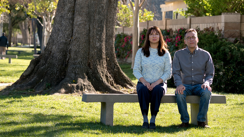 June (Maya Rudolph) and Oscar Hoffman (Fred Armisen) sit next to each other on a stone bench outside in Forever (2018)