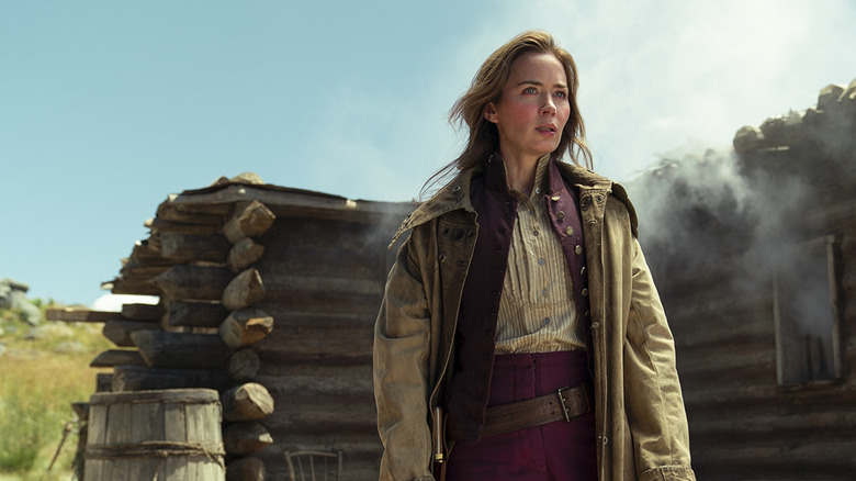 Cornelia Locke (Emily Blunt) stands by a smoldering cabin in The English