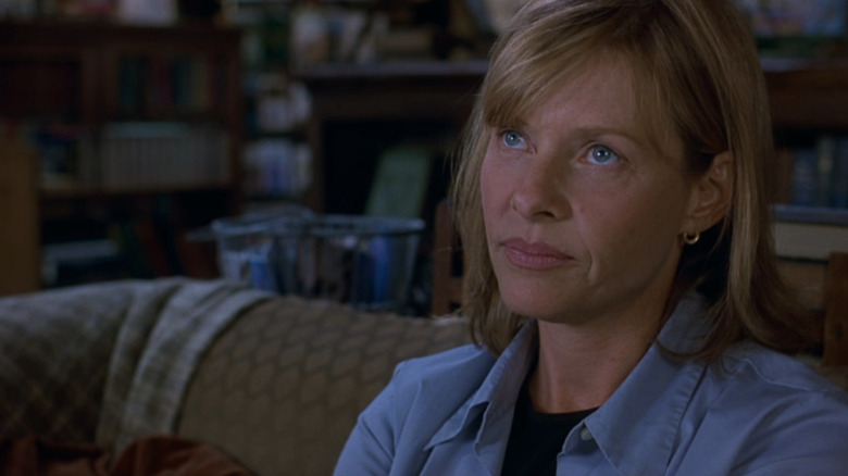 Kate Capshaw with blonde hair, bangs and blue shirt sitting on coach in The Love Letter