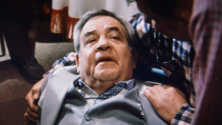Tom Bosley as Sidney Preston in grey suit lying down with someone's arms around him in Million Dollar Mystery