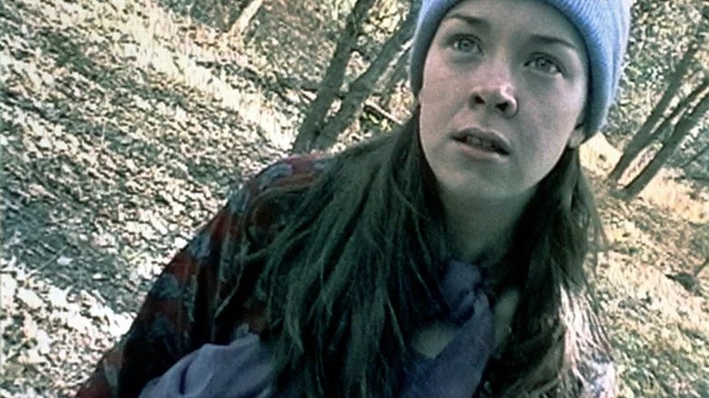 Heather Donahue as Heather standing in the woods looking toward the camera in The Blair Witch Project