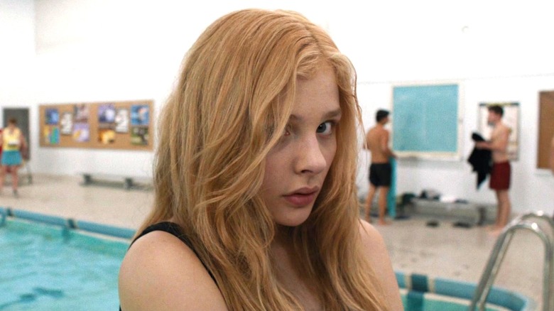 Chloë Grace Moretz as Carrie standing by indoor pool looking at the camera in Carrie