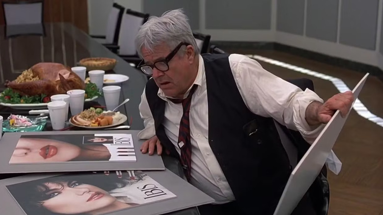 George Petrie as Neal's boss stares at advertisements in Plane, Trains, and Automobiles