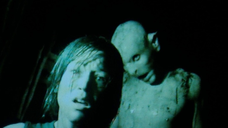 A crawler standing behind Beth (Alex Redi) in The Descent