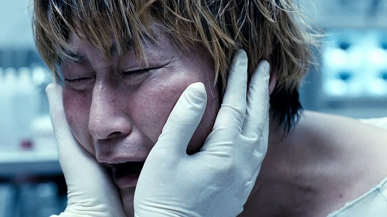 Park Gang-du (Song Kang-ho) crying while face is held by gloved hands in The Host