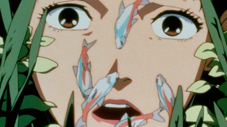 A woman stares into the camera with a shocked look on her face as fish swim over her in Perfect Blue