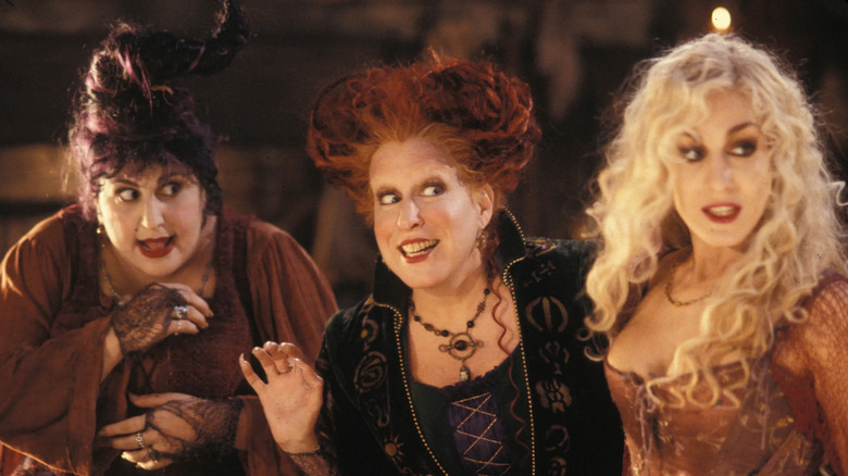 Kathy Najimy, Bette Midler, and Sarah Jessica Parker as the Sanderson sisters stand side-by-side in Hocus Pocus