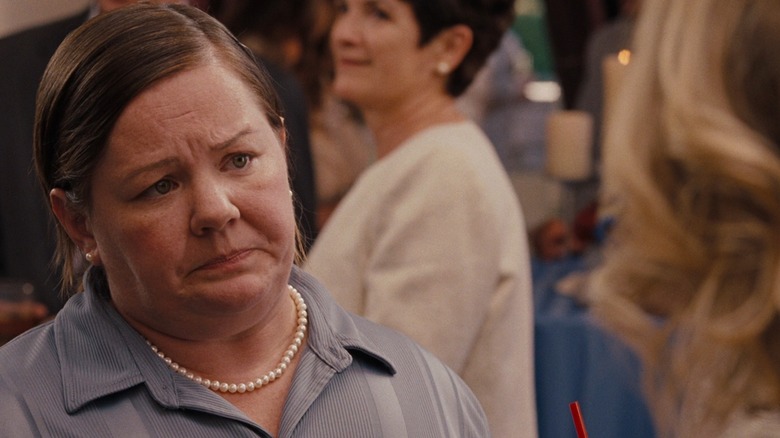 Melissa McCarthy as Megan wearing a pearl necklace and looking disappointed in Bridesmaids