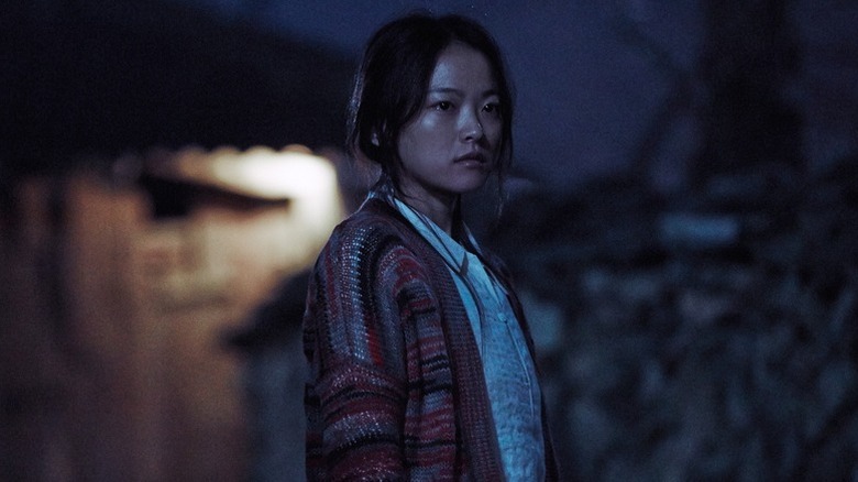 Moo-myeong (Chun Woo-hee) stands solemnly at night in The Wailing (2016)