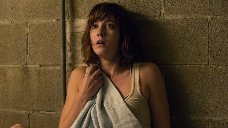 Mary Elizabeth Winstead as Michelle holding a blanket against a wall in 10 Cloverfield Lane