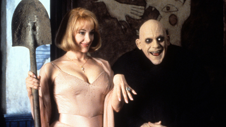 Joan Cusack as Debbie with a shovel and ring next to Christopher Lloyd as Fester in Addams Family Values